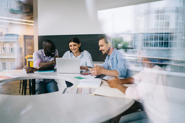 Multiethnic workers discussing ideas and smiling in light office