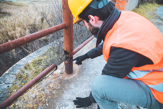 Ingegnere chimico sta valutando i danni della corrosione generalizzata sulla ringhiera di un ponte