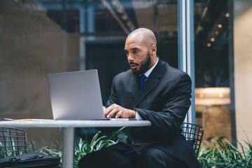 Serious executive man in suit surfing laptop