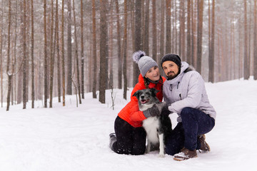young couple with a dog in the winter forest