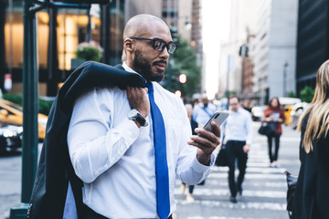 Black confident businessman browsing on cellphone on street