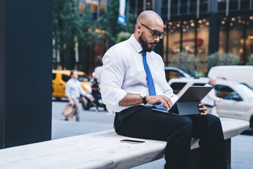 Black entrepreneur typing on tablet outside