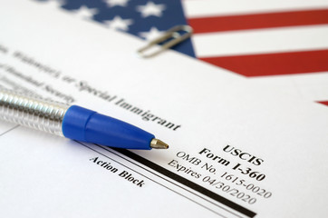 I-360 Petition for Amerasian, Widower or special immigrant blank form lies on United States flag...