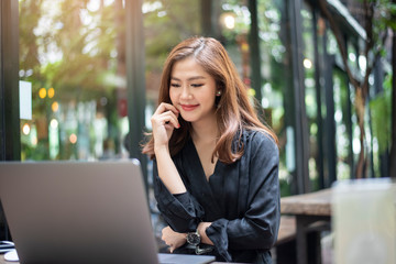 Smart Asian female is working with laptop computer