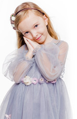 Little fashionable red-haired girl in a gray dress with a wreath on her head posing on a white background