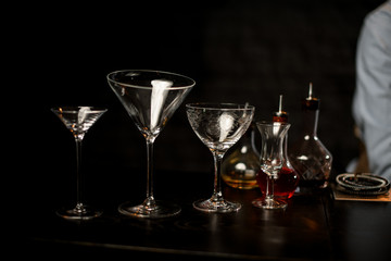 Martini glasses, another cocktail glass and bottle with bitter on the bar counter