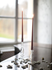  two burning candles on a piano in glass candlesticks