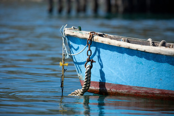 Rowboat anchored in bay with nautical rope