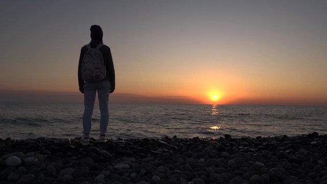 A tourist girl admires the sunset on the beach. Romantic scene. Silhouette