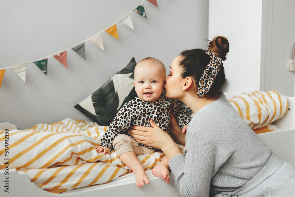 Wall mural Portrait of Positive mother and child laughing and playing on the bad.