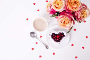 Mini romantic dessert cake for Valentine's Day with roses. Sweet cookies with cream topping and red heart for decor on white. Close-up, copy space.