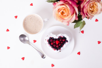 Mini romantic dessert cake for Valentine's Day with roses. Sweet cookies with cream topping and red heart for decor on white. Close-up, copy space.