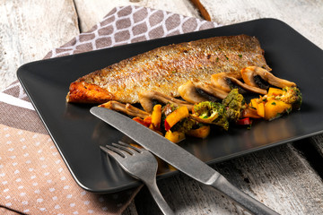 Grilled Fish Fillet. Grilled fish with pasta and vegetables on the plate, white wooden table.