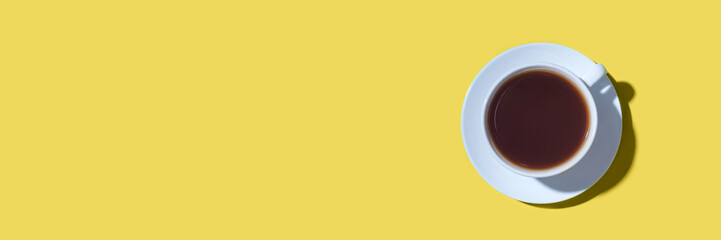 A cup of black coffee or tea on a yellow background. Minimal concept. Flat lay, top view.