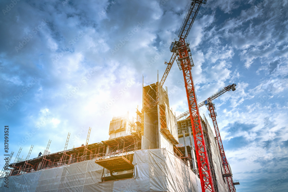 Wall mural a team of workers is working and a large crane on the modern multi-floor building site to complete t