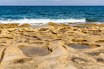 Blue emerald Mediterranean sea water with stone beach in Sliema, Malta. Unearthly rocky Malta shore.