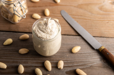 Homemade organic vegan butter made from almonds on a wooden background.