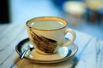 A Cup of coffee on a saucer in a coffee shop.