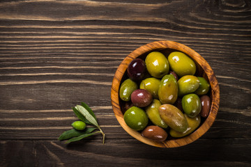 Black and green olives on wooden table.