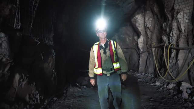 A miner goes through an underground section in the mine. He inspects the chips. He wears a safety helmet, a reflective vest, with a self-rescue vest. It's all for safety.