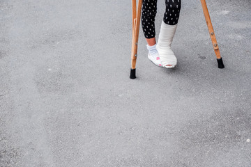 child using crutches and broken legs for walking outdoor,Close up. broken leg, wooden crutches,...