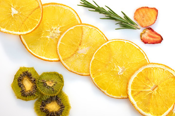 Circles of slices of dried orange kiwi and strawberry on white background.