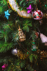 Christmas tree at on Christmas Eve at home decorated with different retro vintage glass toys with pretty lights and garlands, toy Nutcracker, toy globe and shiny colored stars