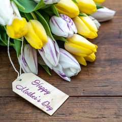 Happy Mother's Day background square - Bouquet of yellow and white tulips with a pendant on a rustic wooden table