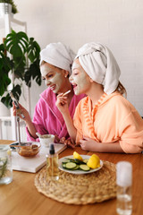 Obraz na płótnie Canvas Mother and daughter in bathrobes and towels on head using natural cosmetics and having fun together at home