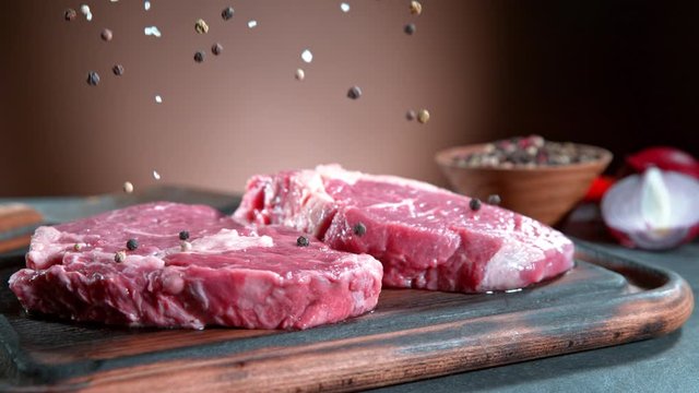 Super Slow Motion Shot of Falling Pepper and Salt on Fresh Meat at 1000fps.