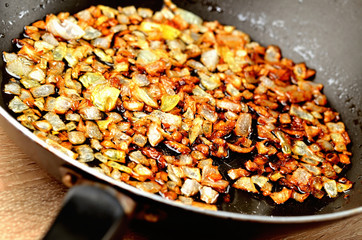 Golden chopped onion fried in oil in pan. Close-up