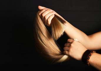 The male hand holds sections of hair for extension.Different types of hair.Blond,red and brown-haired sections.Hair extensions concept.