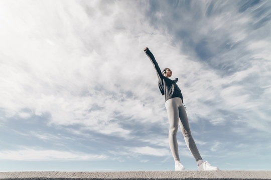 dynamic photo from below: the girl raised her hands to the sky, where unusual clouds of her perspective looking into the distance emphasize her figure