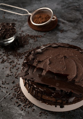 Raw chocolate cheesecake on dark grey background. Healthy organic dessert pie. Cacao and chocolate around