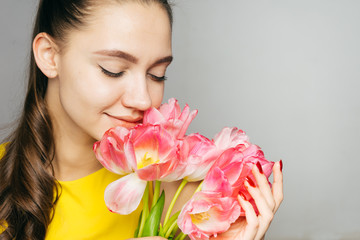 girl with pleasure sniffs tulips covering her eyes