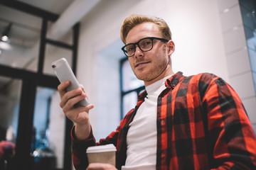 Calm guy browsing smartphone at workspace