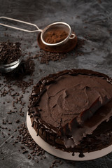 Raw chocolate cheesecake on dark grey background. Healthy organic dessert pie. Cacao and chocolate around