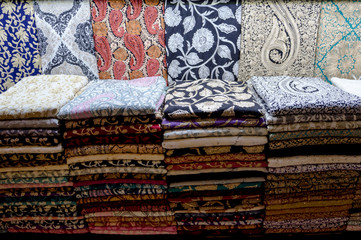 Multicolored fabrics are laid out on the sales counter in a rolled-up form.