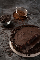 Raw chocolate cheesecake on dark grey background. Healthy organic dessert pie. Cacao and chocolate around