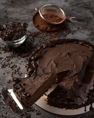 Raw chocolate cheesecake on dark grey background. Healthy organic dessert pie. Cacao and chocolate around