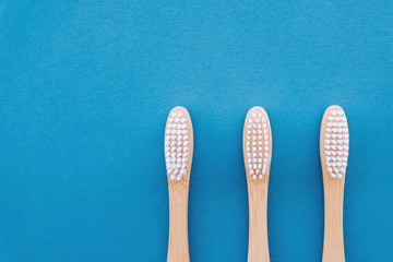 Stylish natural eco friendly toothbrushes with wooden bamboo handle on blue background.