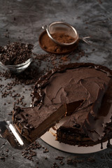 Raw chocolate cheesecake on dark grey background. Healthy organic dessert pie. Cacao and chocolate around