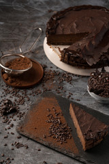 Raw chocolate cheesecake on dark grey background. Healthy organic dessert pie. Cacao and chocolate around