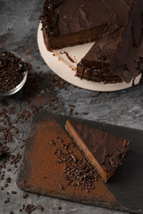 Raw chocolate cheesecake on dark grey background. Healthy organic dessert pie. Cacao and chocolate around