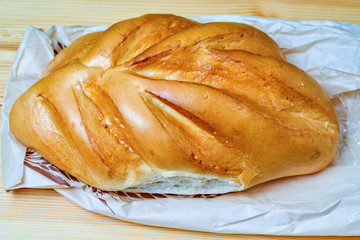loaf of white bread lies on a wooden board.