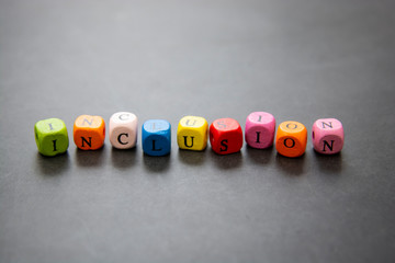 Inclusion text of multi colored cubes on dark background. Inclusive social concept.