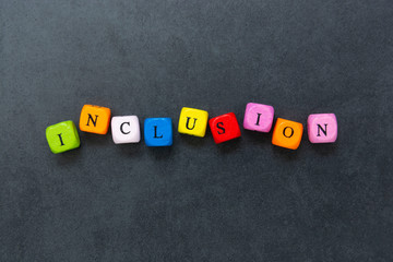 Inclusion text of multi colored cubes on dark background. Inclusive social concept.