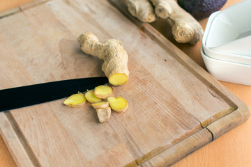 frisch aufgeschnittene Ingwer-Wurzel in Scheiben mit einem Messer auf einem Holzbrett