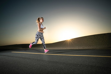 Fototapeta na wymiar Athletic woman running during sunset on running track