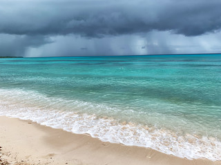 Cloudy day on the beach. Rain on the coast during a beach holiday. Rainy season in the Dominican Republic. Azure water in the ocean during a thunderstorm. Clouds and showers over the sea in the tropic
